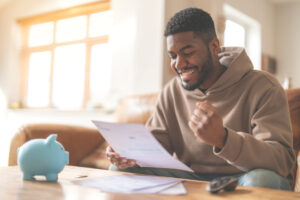 Smiling homeowner reviewing financial documents at a table, symbolizing loan approval, savings, or successful financing.